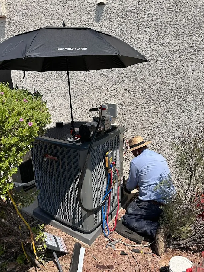 HVAC technician performing outdoor AC maintenance in Los Lunas
